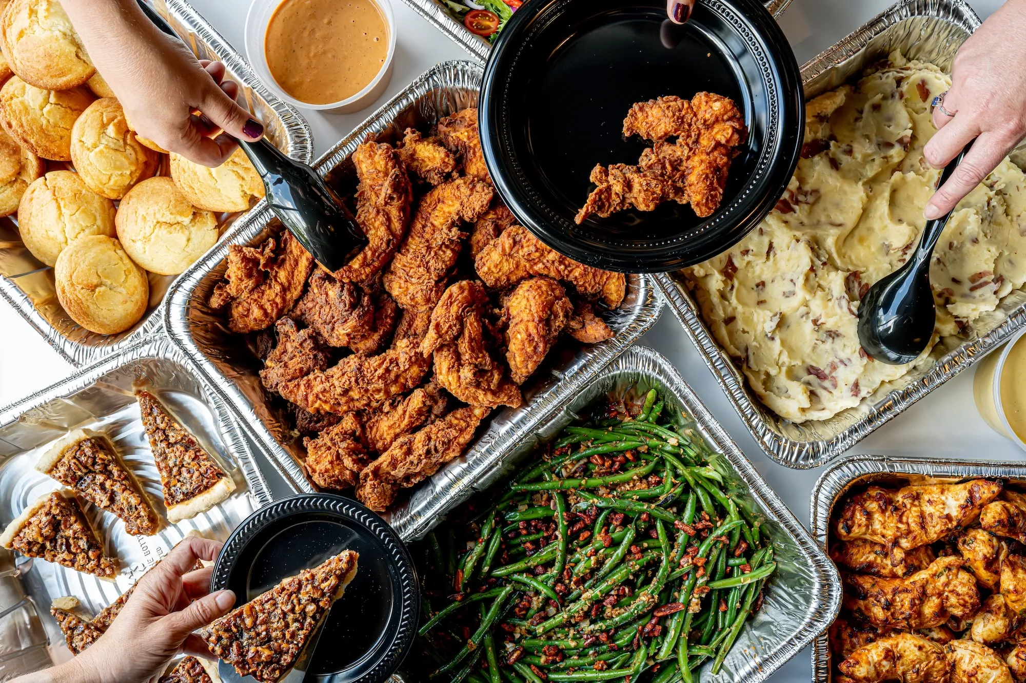 a piece of pecan pie on a plate next to chicken tenders and green beans
